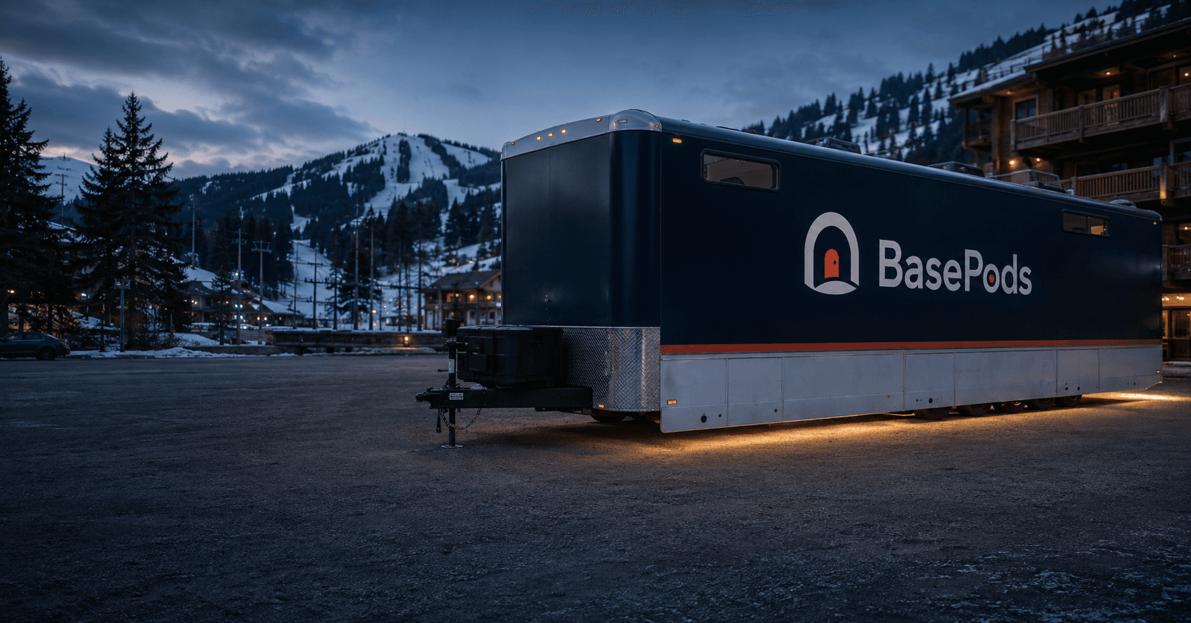 A BasePods PeakPods trailer parked at a ski resort at dusk, mountain slopes in the background